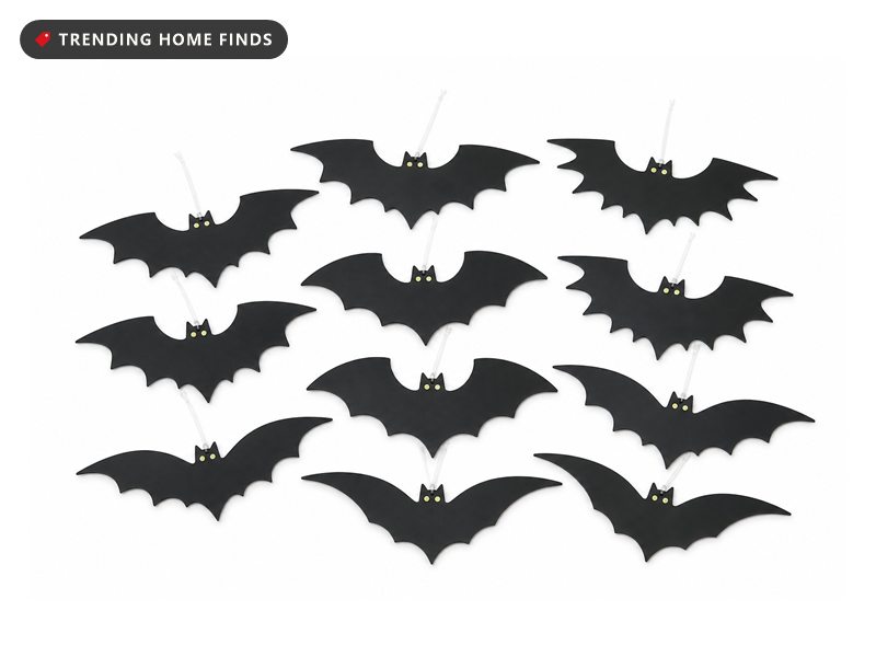 Twelve flat matte black bat cutouts with swept pointed wings and small pale eye dots, spread out with clear hanging line at each one.
