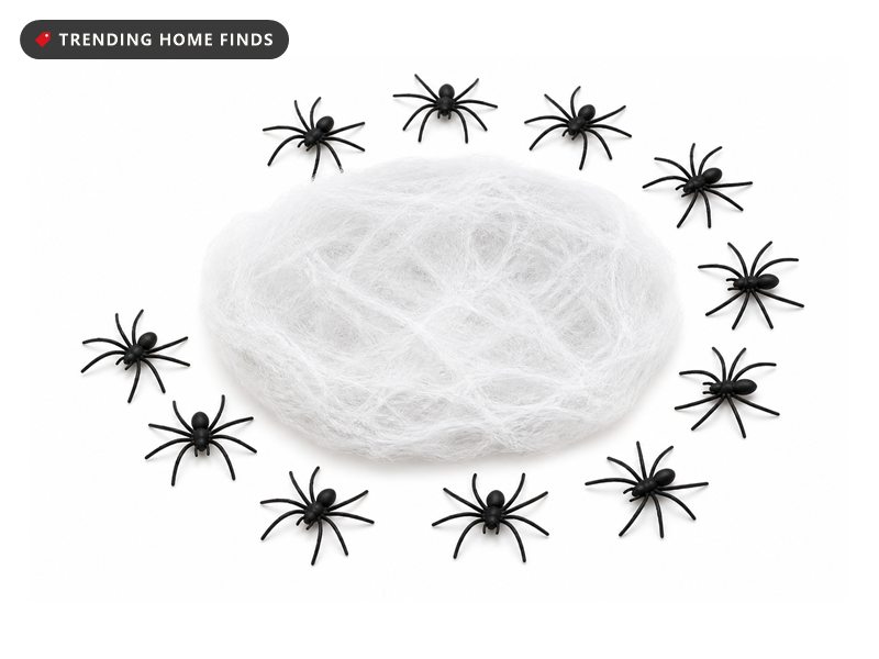 A loose mound of stretchable white cobweb fiber pulled open beside a spread of small black plastic spiders with long thin legs.