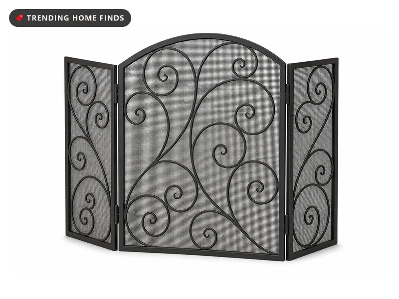 A black wrought iron three panel fireplace screen with an arched center panel, fine mesh infill and applied scrollwork, standing open.
