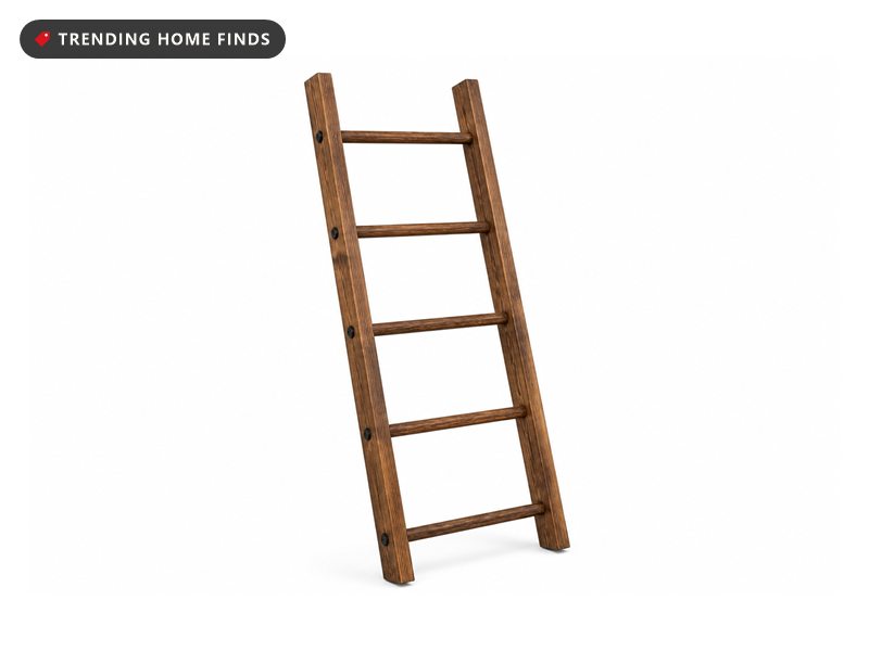 Wooden five rung blanket ladder leaning against a wall with throws draped over its rungs