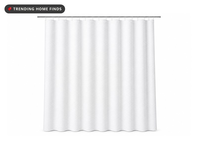 White waffle weave shower curtain hanging from a chrome rod on metal hooks, textured diamond pattern across the fabric.