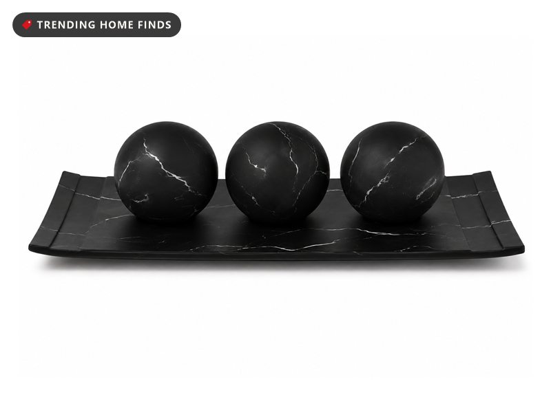 Black marble look tray holding three matching decorative orbs