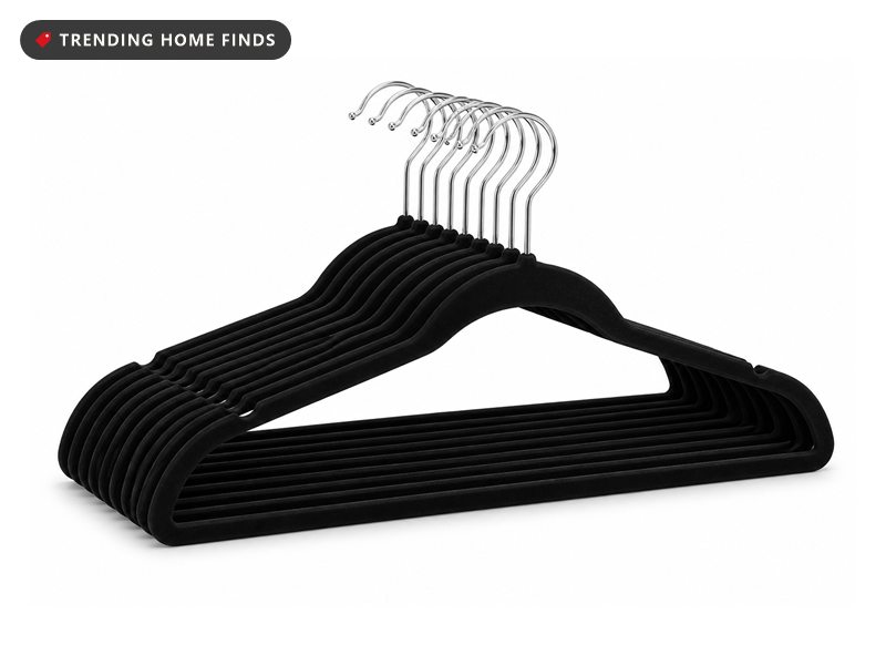 A stack of slim black velvet clothes hangers with silver swivel hooks.
