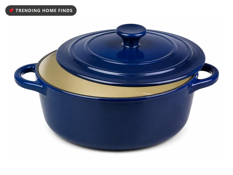 A blue enameled cast iron dutch oven with its lid tilted on a wooden counter beside a rain-streaked window, steam rising from inside.