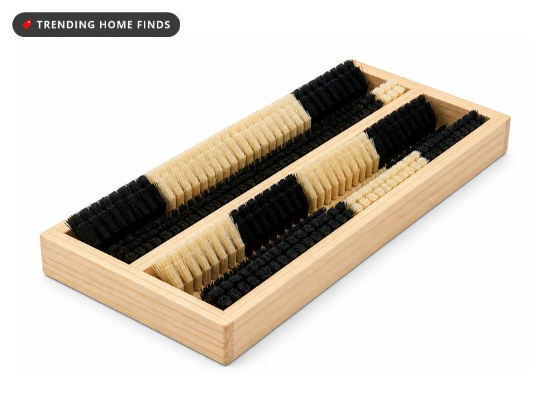 A pale wood framed boot brush with two channels of stiff black and cream bristles.