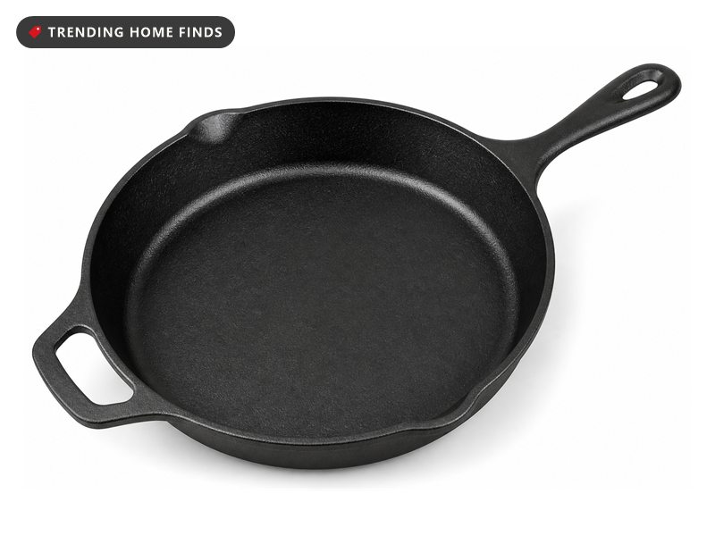 A black cast iron skillet with a long handle, a helper handle and two pour spouts.