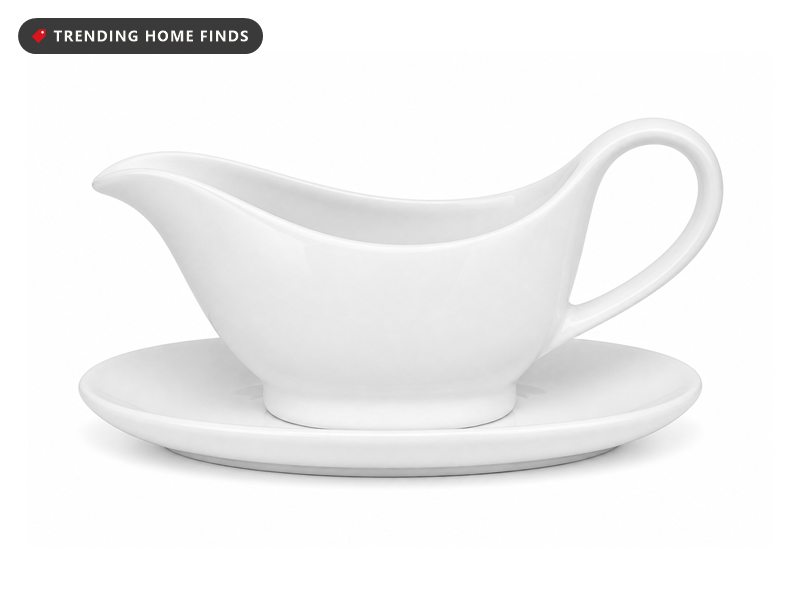 A white ceramic gravy boat resting on its matching oval saucer.