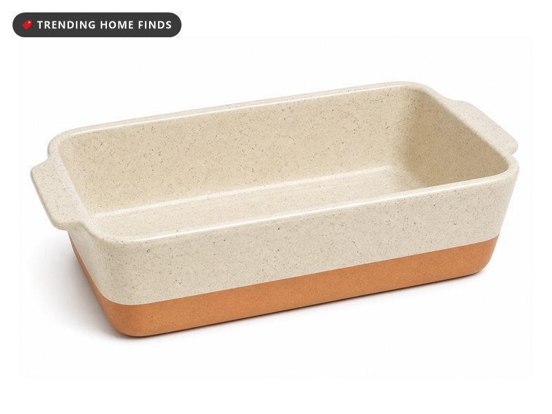 A speckled cream ceramic loaf pan with an unglazed terracotta base band and a short handle lip at each end.