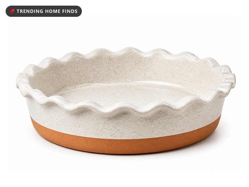 A speckled white ceramic pie dish with a fluted rim and a bare terracotta band around its base.