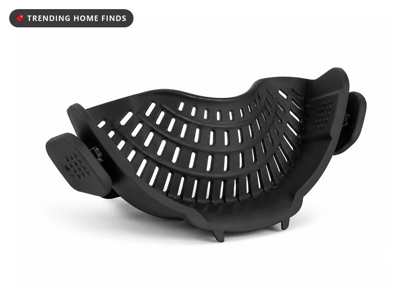 Black curved silicone strainer with oval slots and side clips that snaps onto a pot rim