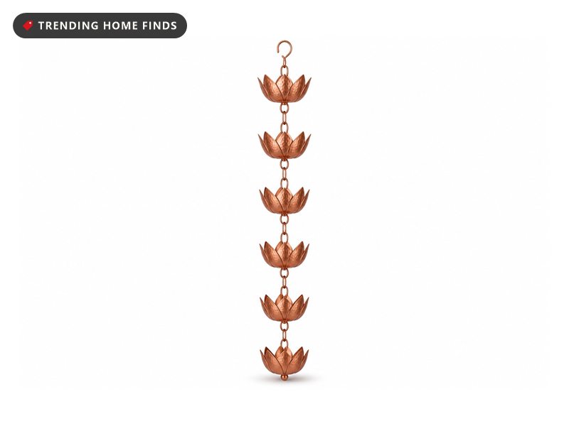 Pure copper lotus cup rain chain with rain running cup to cup against a dark siding wall