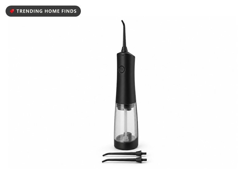A black cordless water flosser standing in a marble tray with folded towels and a small trailing plant on a bright bathroom counter.