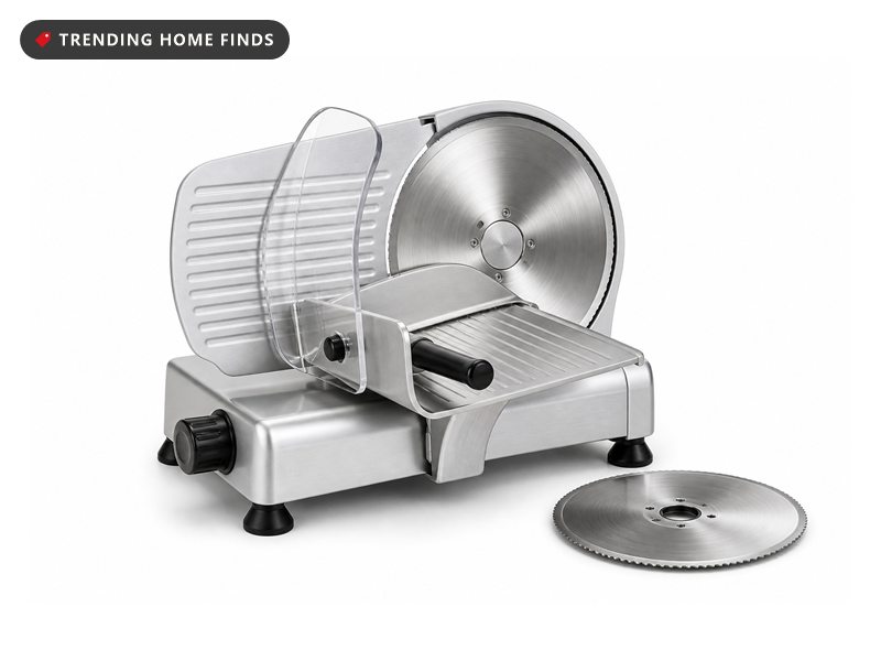 Brushed silver countertop meat slicer with a large circular stainless blade, clear guard and angled food tray.