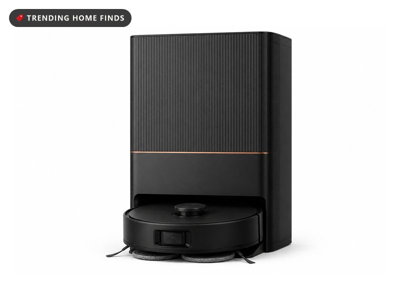 Black dreame L40 Ultra robot vacuum docked at its tall all-in-one self-emptying base, beside a phone showing the app map