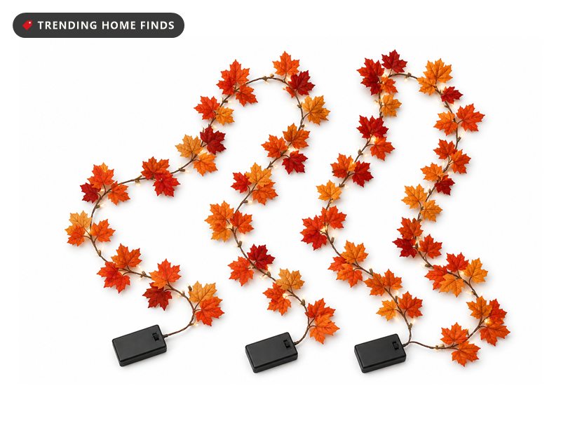 Three strands of artificial maple leaves in burnt orange, red and gold on brown wire with small warm LEDs lit between them.