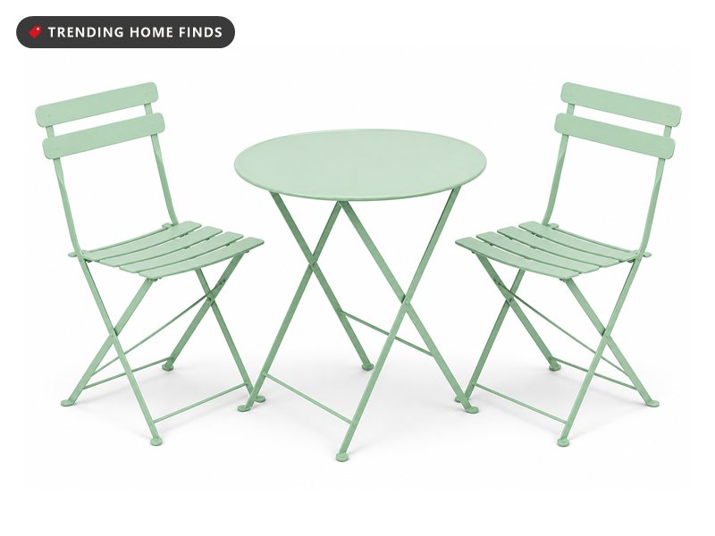 A mint green folding bistro table with two slatted chairs.
