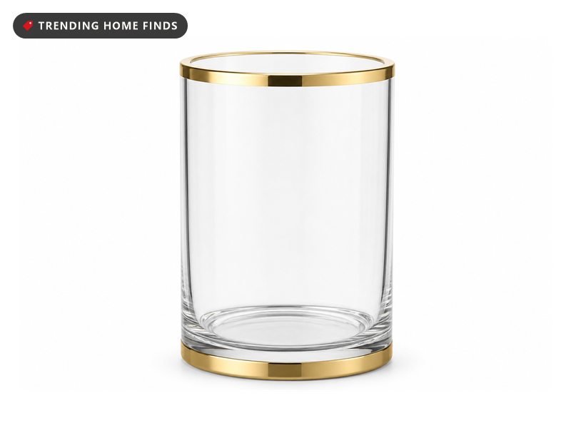 A clear glass brush holder with a gold rim, filled with white pearls holding brushes upright.