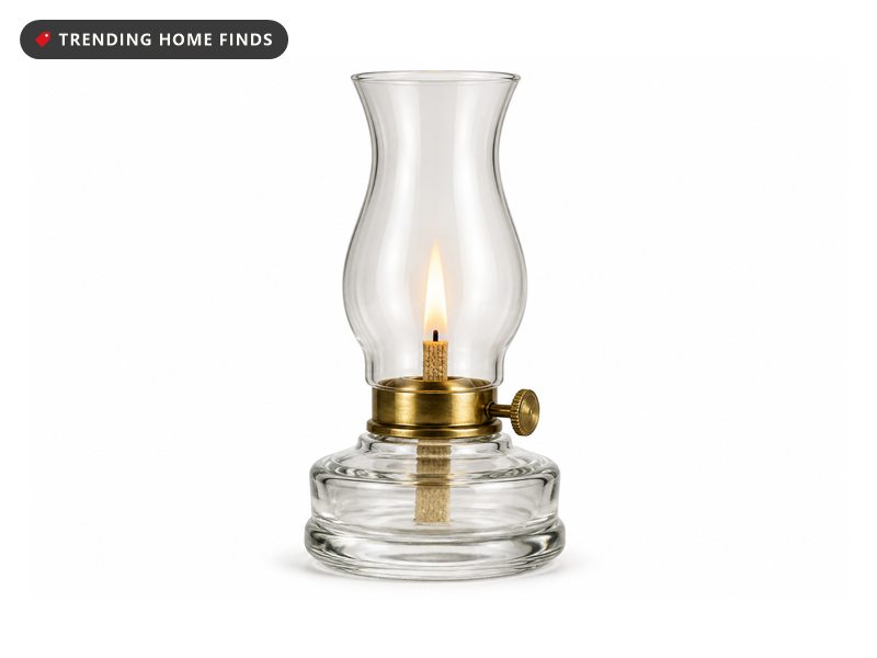 A clear glass chamber oil lamp with a brass collar and a tall chimney, wick lit.