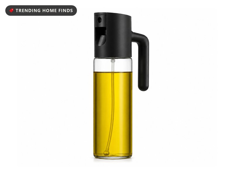 Clear glass olive oil bottle filled with golden oil, topped with a black pump sprayer head and a side handle