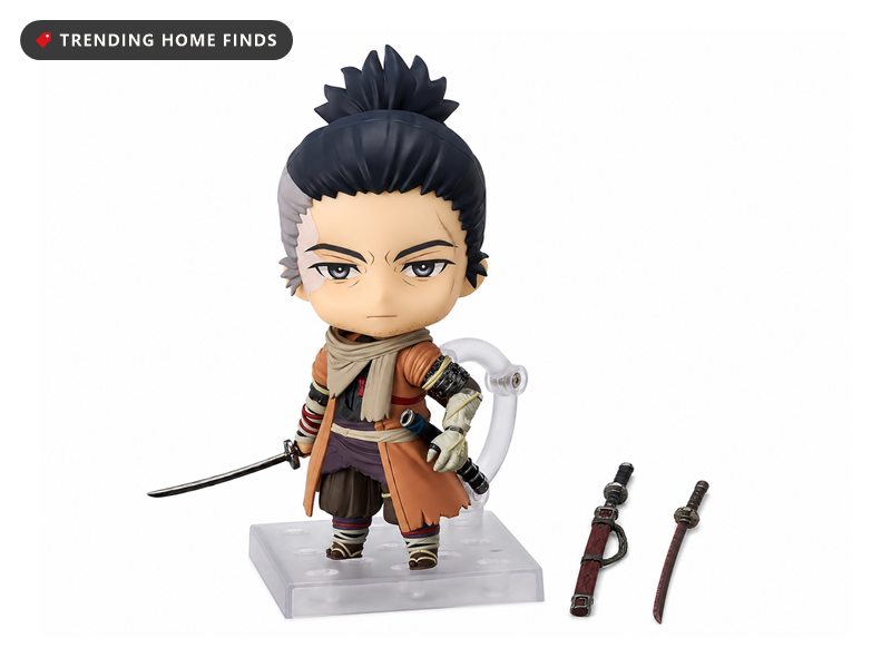 Nendoroid figure of the Wolf from Sekiro with an orange coat, prosthetic arm and drawn katana on a clear stand, beside two sheathed swords