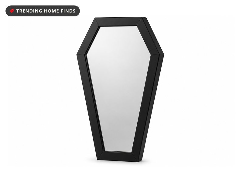 A black wooden coffin shaped mirror with a mitered hexagon frame and mirror glass set flush inside it.