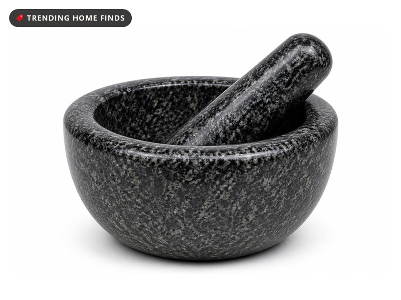 A black and gray speckled granite mortar with a round bowl and a thick matching pestle resting inside it.