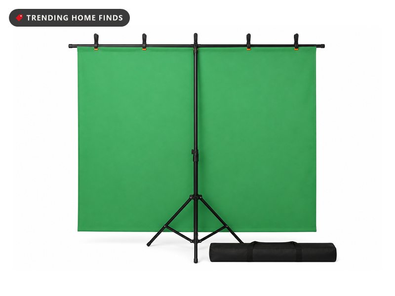 A green fabric backdrop on a black T shaped stand with spring clamps and a carry bag beside it.