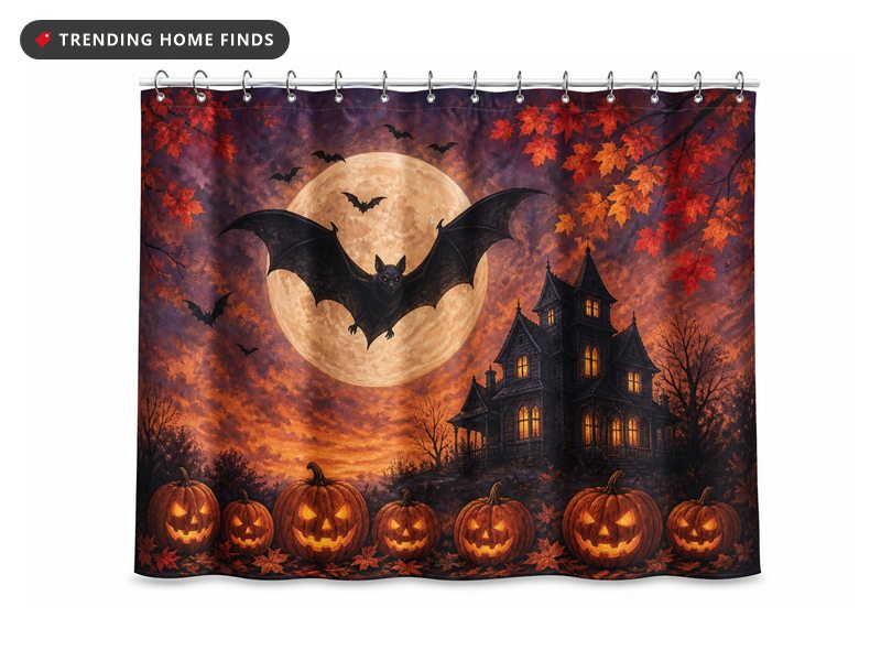 A printed shower curtain showing bats crossing a full moon above lit pumpkins and a dark gabled house.