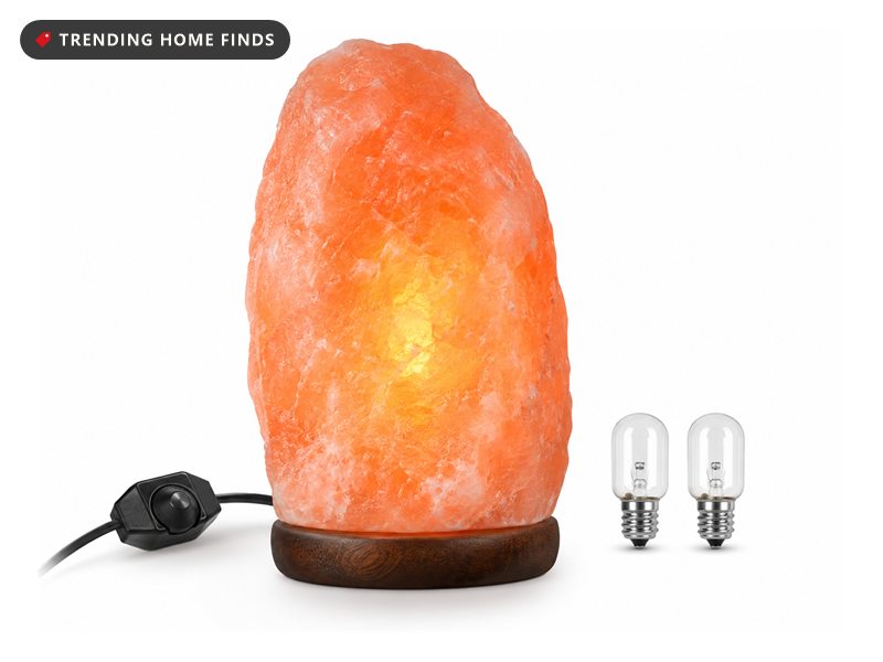 Glowing pink Himalayan salt lamp on a wooden base with two spare bulbs