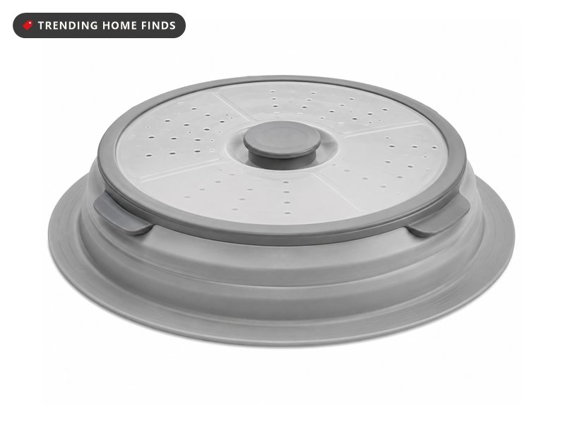 Grey collapsible microwave splatter cover with vent holes across the top, shown partly folded down