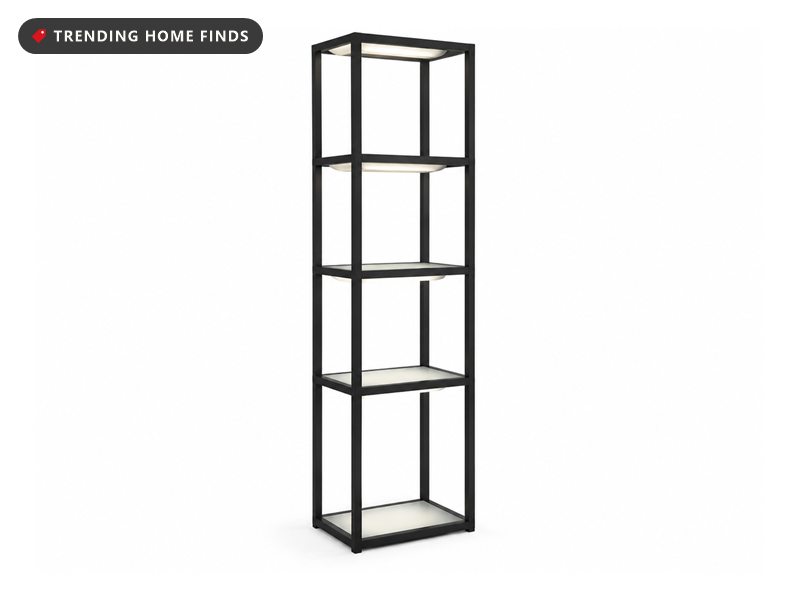 Tall black metal open-frame display tower with lit shelf panels glowing warm white from a dark frame