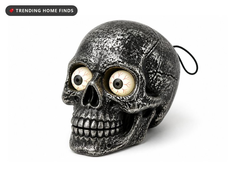 A weathered silver and black skull with round bloodshot eyeballs lit from within, a cord loop at the back of the cranium.