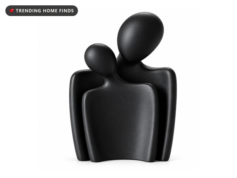 Black abstract sculpture of a couple with one figure resting its head on the other