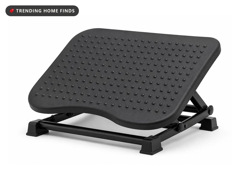 A black tilting footrest with rows of raised massage bumps on a folding frame with four flat feet.