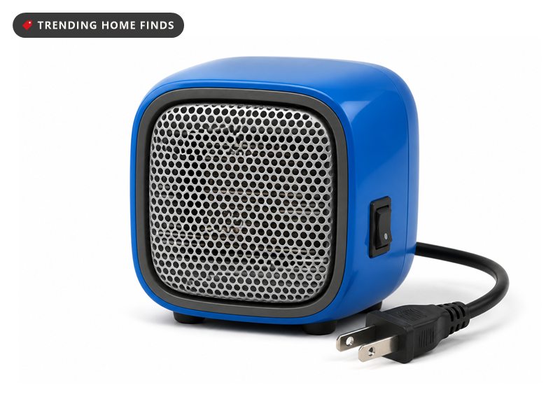 Small ceramic personal space heater with a carry handle sitting on a desk