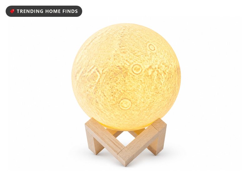 Glowing moon lamp on a wooden stand next to a color remote
