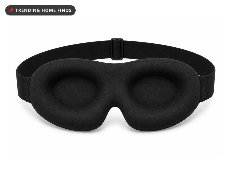 Black contoured blackout sleep mask with moulded eye cups and an adjustable strap, on white.