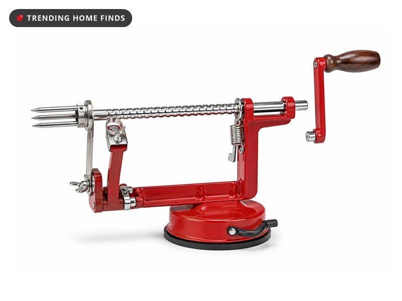 Red cast metal crank apple peeler with a chrome spiral shaft, wooden handle and a round red vacuum suction base.