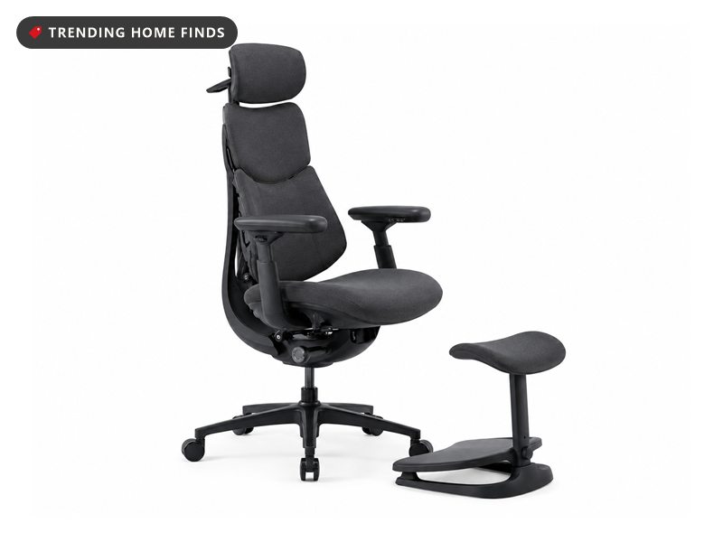 Dark gray ergonomic office chair with headrest, adjustable arms and a separate cushioned footrest ottoman