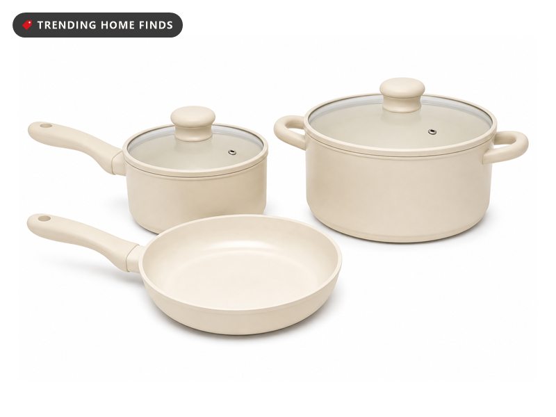 Three cream ceramic pans with clear glass lids on a kitchen counter in soft overcast daylight, the non toxic swap for an old nonstick set.