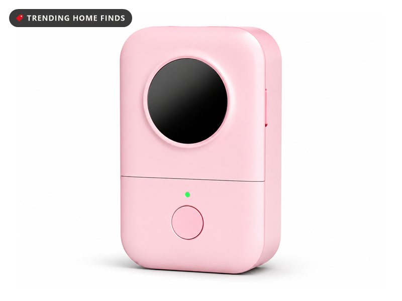 Small pink Phomemo Bluetooth label maker with a round black label outlet on the front and a single power button below it