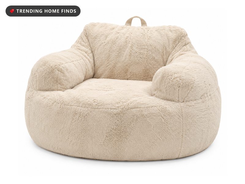 Large cream faux fur bean bag chair with padded armrests, a high back and a fabric carry handle on top