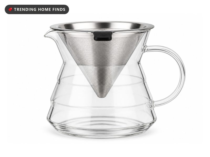A clear glass pour over carafe with a faceted lower body, a loop handle and a stainless steel cone filter seated in its mouth.