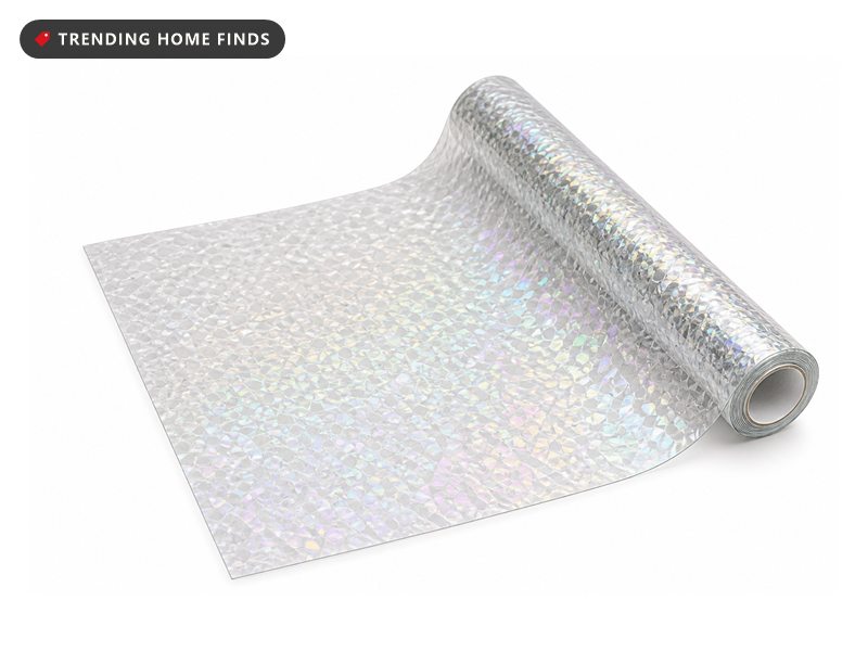 Roll of clear stained glass patterned privacy window film, partly unrolled, on a white background.
