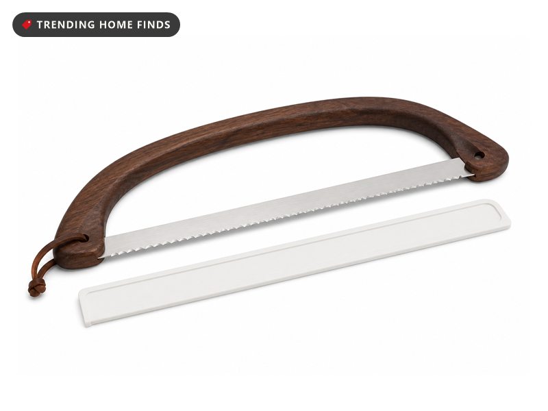 Bow-shaped bread knife with a long serrated blade stretched across a curved dark walnut handle, with a white blade sheath.