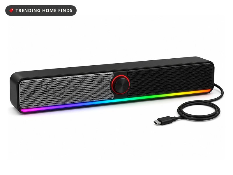 Slim black desktop soundbar with a silver mesh section, a black mesh section, a red ringed volume knob and a lit color strip along the front edge.