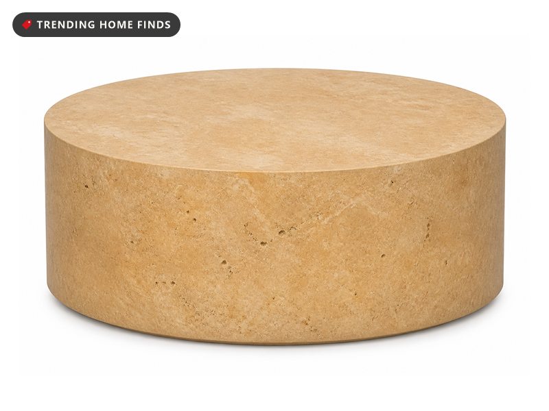 Round honey toned faux stone concrete coffee table on a patio with a linen runner nearby