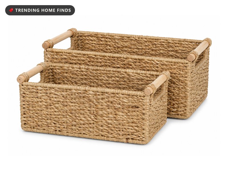 Two handwoven seagrass storage baskets with pale wooden handles.