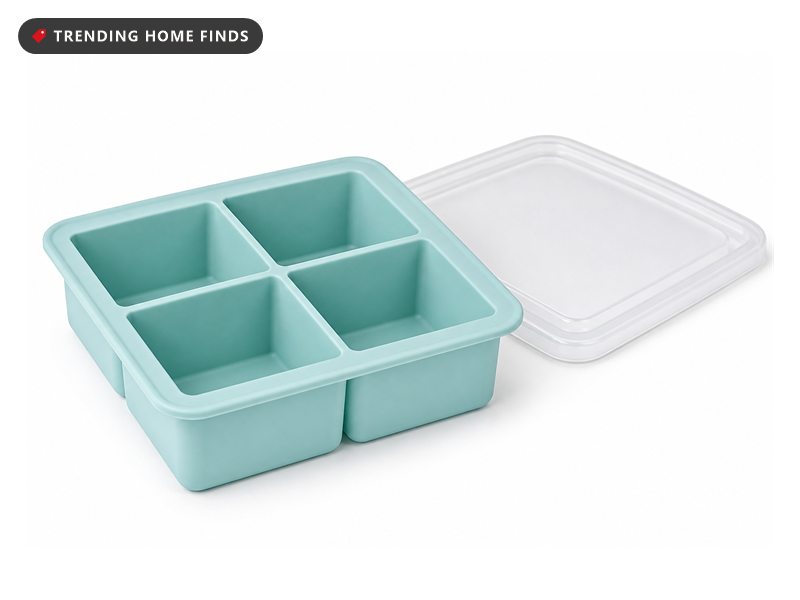 Freezer organization in a home kitchen at golden hour, an open drawer of aqua silicone trays holding solid frozen soup blocks.
