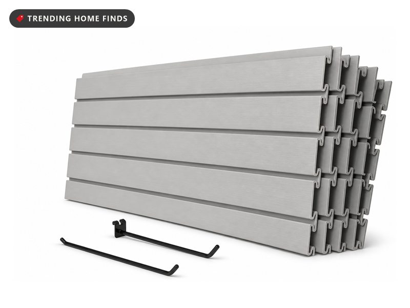 A grey slatted PVC panel wall in a garage holding hooks and hand tools, bright midday light across it, part of a simple garage makeover.